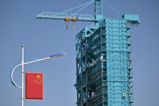 The Long March-2F carrier rocket, carrying the Shenzhou-20 spaceship, is seen encased in blue scaffolding on the launch pad