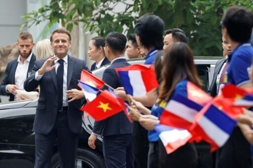 France's President Emmanuel Macron is greeted by flag waving university students in Hanoi